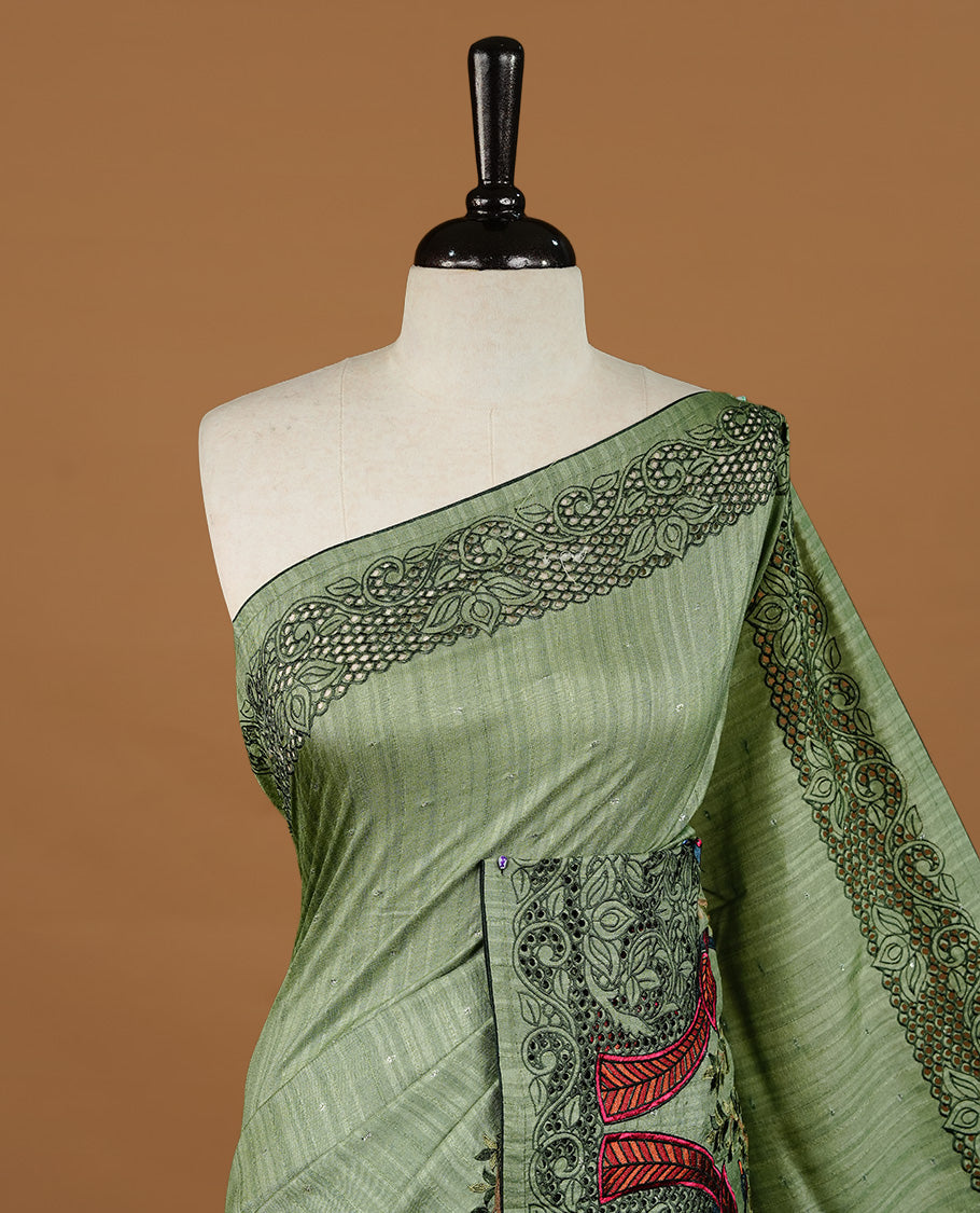 Green colour Semi Tussar silk saree features an intricate cutwork embroidered peacock motifs on border, paired with a matching unstitched blouse piece.