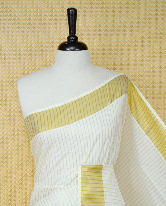 Cream Colur Cotton Kerala Saree Featuring Gold Zari Strips Across On The Body, Classic  Gold Zari Border & Pallu,Paired With A Matching Blouse Piece.