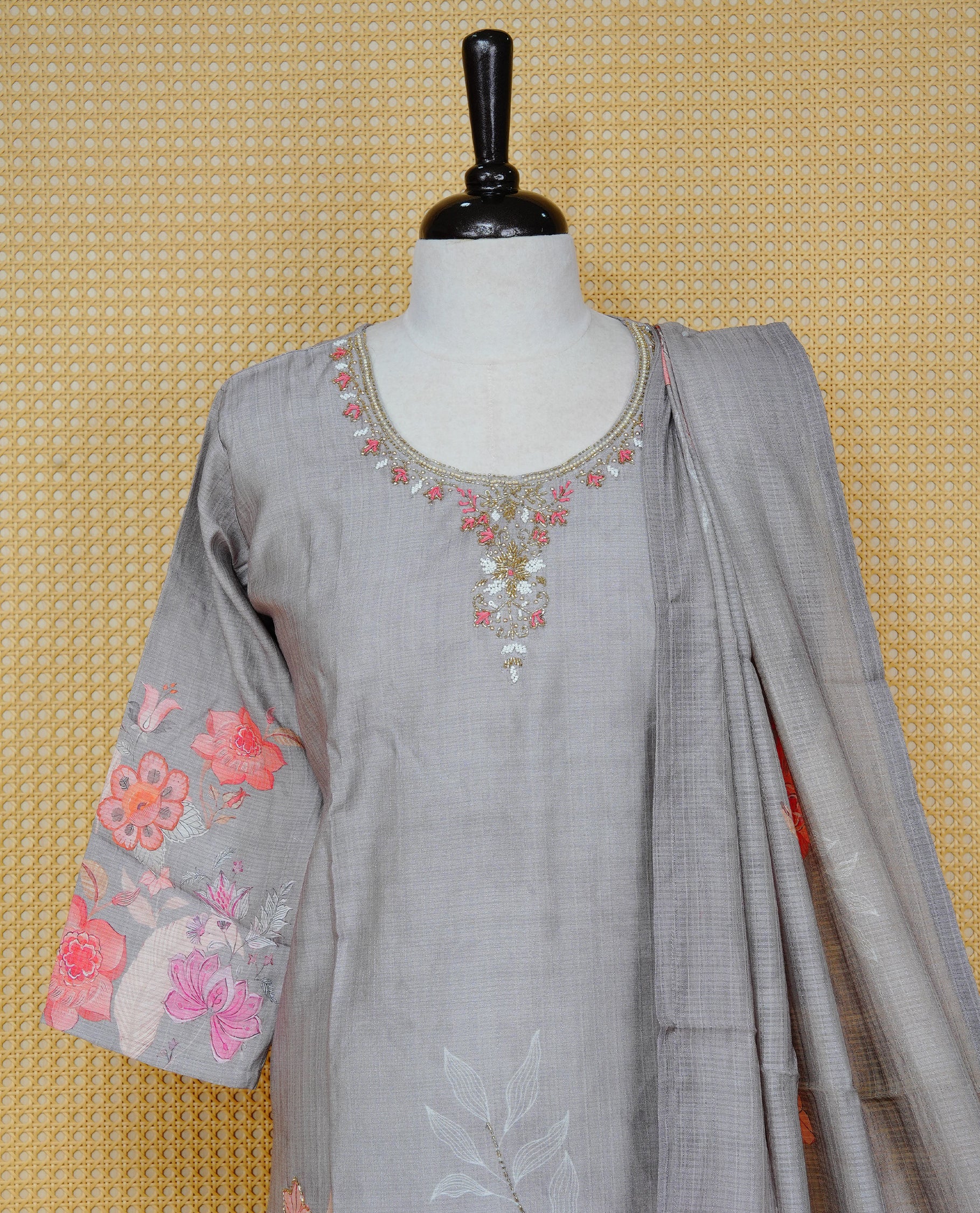 Grey colour churidar set featuring delicate floral prints on the body and intricate bead work on the neckline, paired with a matching floral printed dupatta and solid pants.