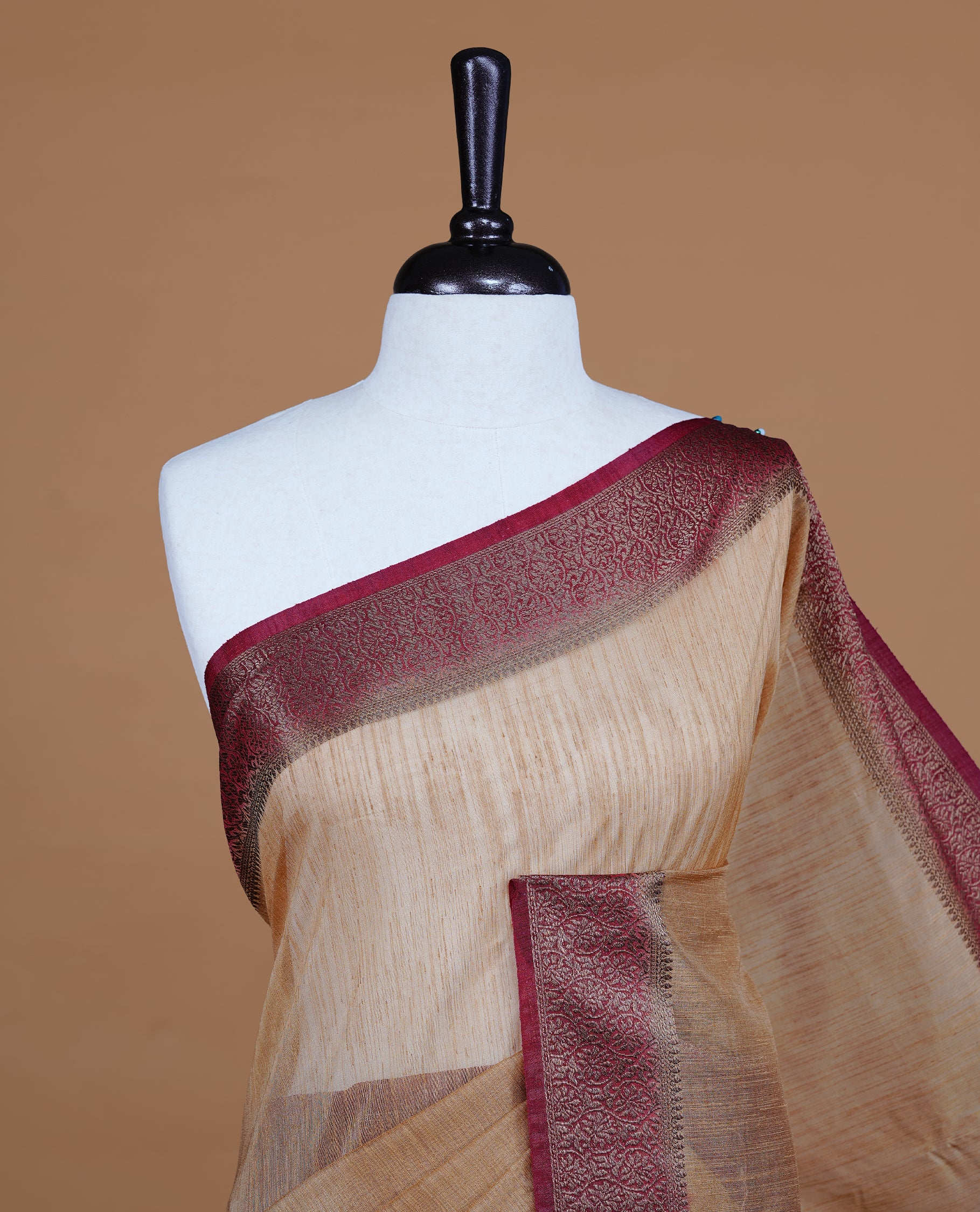 Beige colour Semi linen saree featuring Elegant plain body, complemented by contrast Maroon colour With Antique zari border, paired with matching blouse piece.