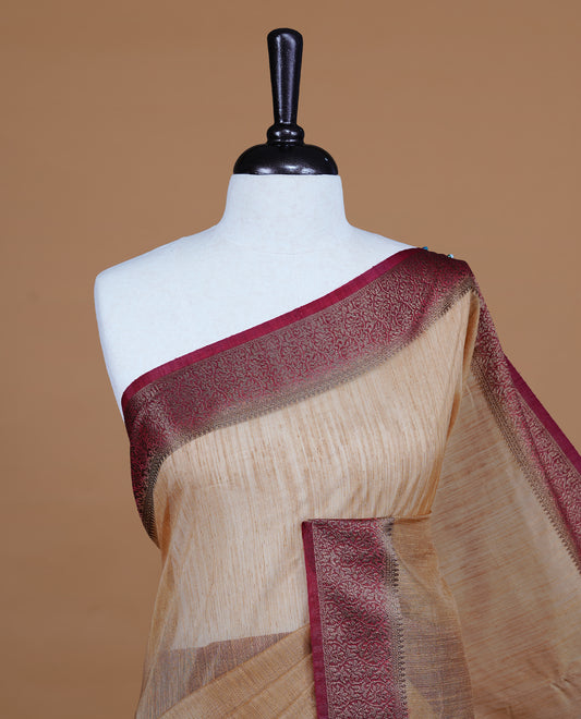 Beige colour Semi linen saree featuring Elegant plain body, complemented by contrast Maroon colour With Antique zari border, paired with matching blouse piece.