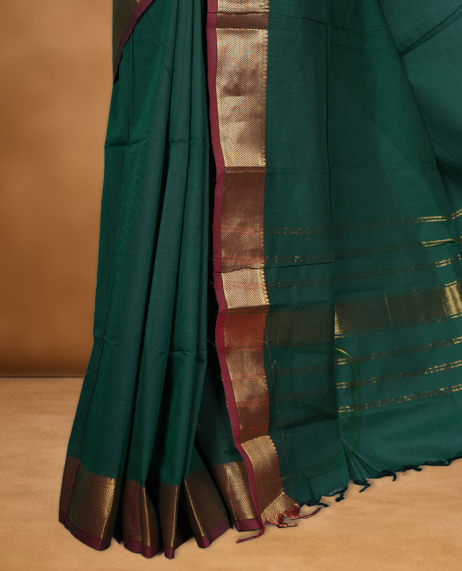 Dark green colour chettinad cotton saree featuring elegant plain body highlighting contrast maroon colour colour with gold zari traditional border, pallu and paired with matching blouse piece.