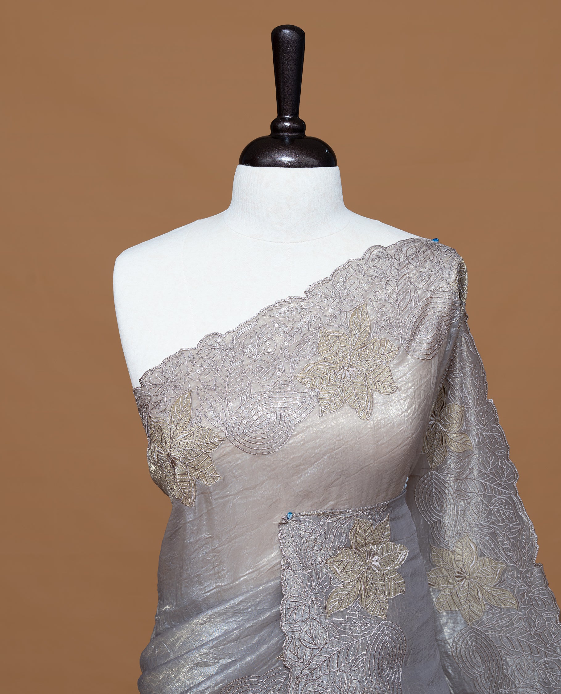 Grey colour Crush Organza Featuring Plain body, Enrich with Floral thread pattern with sequins & scalp border, paired with matching blouse piece.