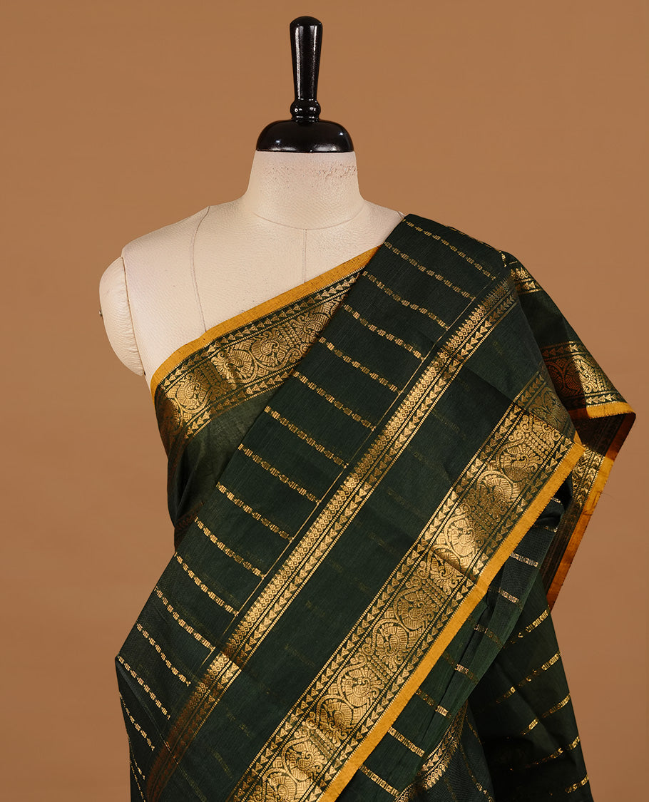 Dark green colour chettinad cotton saree featuring gold zari stripes on body, complemented by self colour with zari  mustard piping border, paired with matching blouse piece.