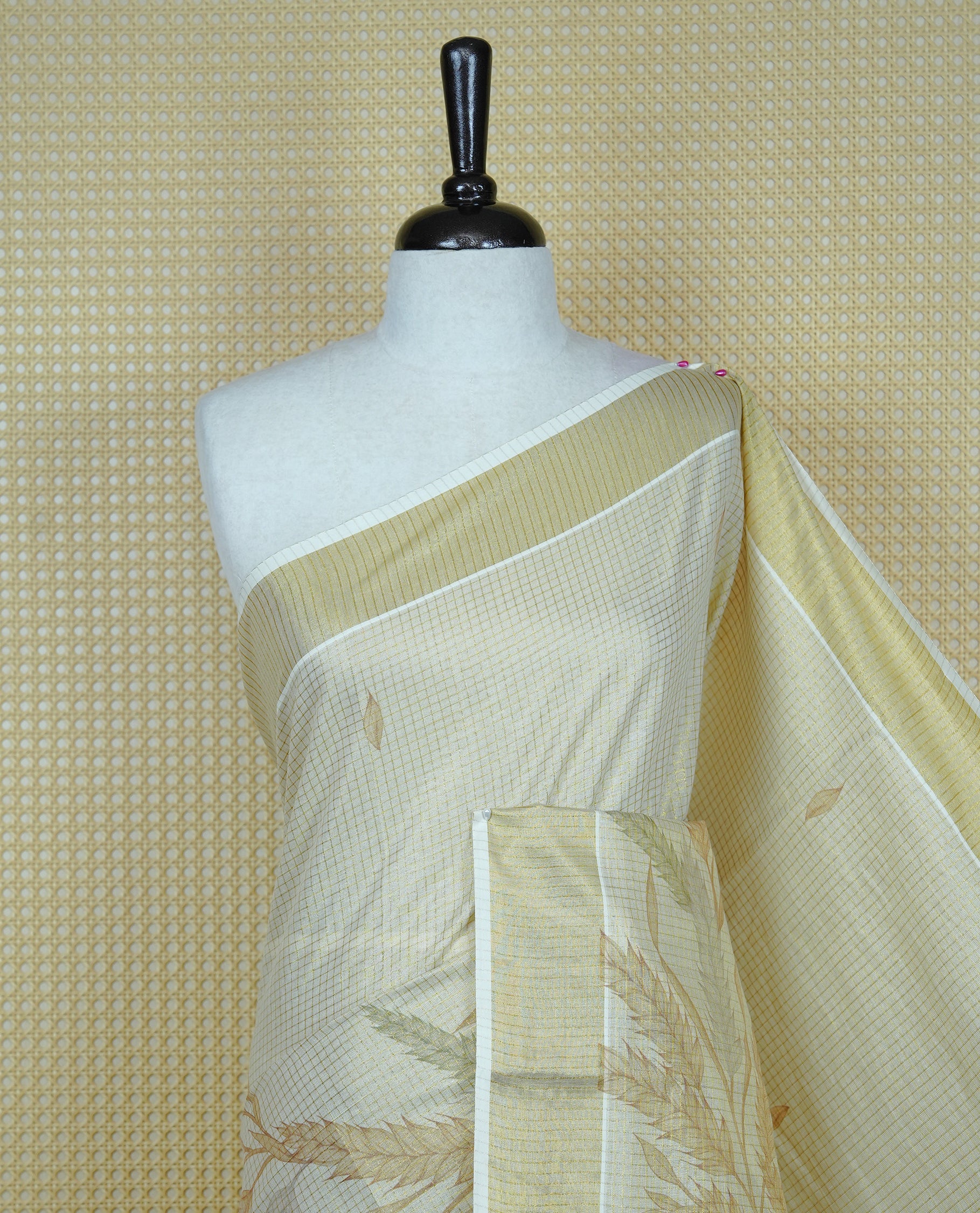 Light gold colour tissue Kerala saree featuring Leaf print & Gold zari check on body, complemented by gold Border, comes with matching blouse piece.
