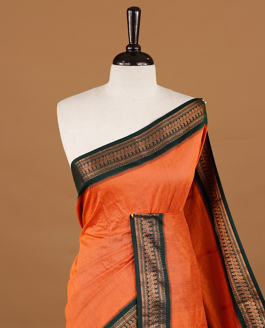 Orange colour kalyani cotton saree featuring gold zari motifs on body, highlighting contrast green  colour with Antique gold zari border, paired with matching blouse piece.