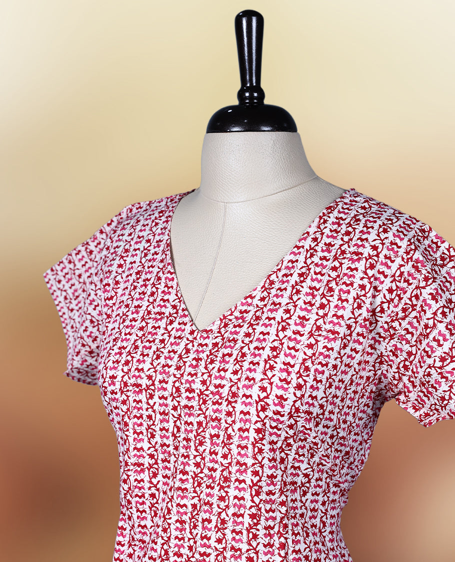 Off white colour kurthi with red and peach colour block style prints, V neckline, and short sleeves, Designed with a flattering silhouette and ruffled hem, perfect for everyday comfort and stylish casual wear.