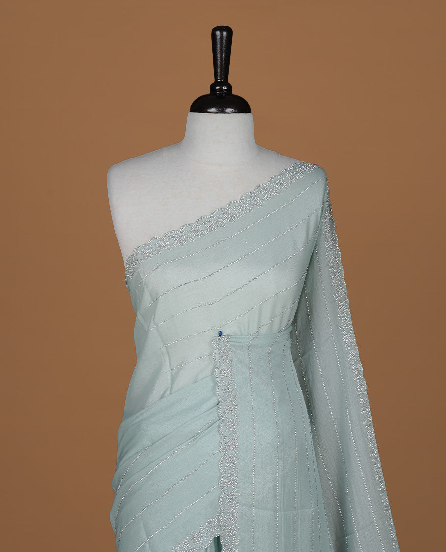 Light blue colour designer saree featuring white stone stripes on body, highlighting white stone with scalp border, paired with matching blouse piece.