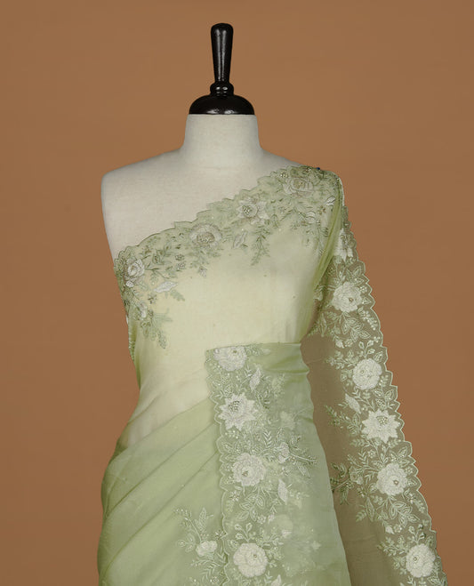 Pastel green colour organza saree featuring thread with cut beats & sequins floral pattern on body, highlighting scalp border, paired with matching blouse piece.