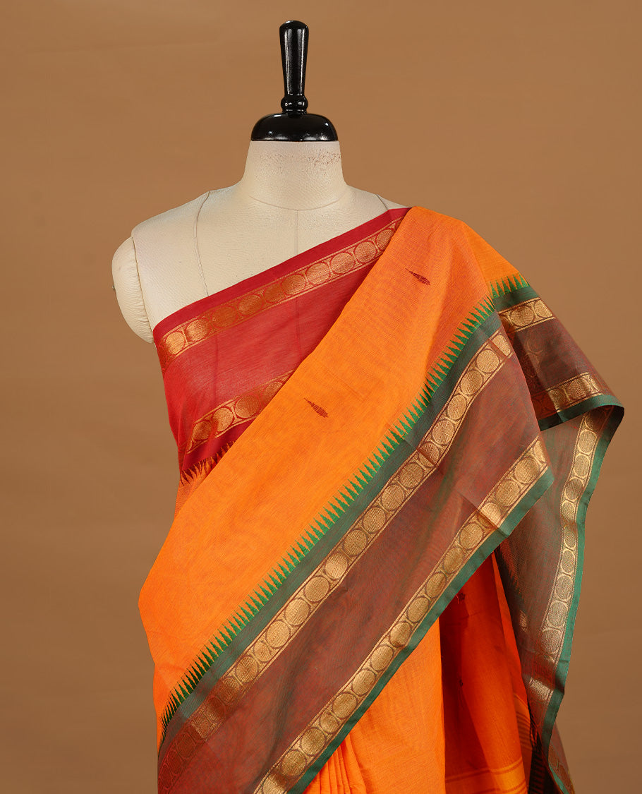 Orange colour chettinad cotton saree featuring motifs on body, complemented by Green colour with zari border, paired with matching blouse piece.