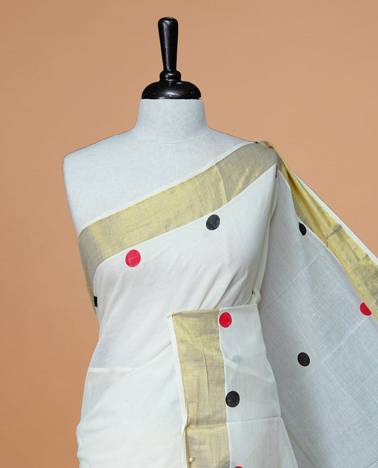 Cream Colour cotton Kerala Saree Featuring  Black & Red Dot Prints On The Body, Complemented By A Traditional Gold Zari Border, Paired With A Matching Blouse Piece.