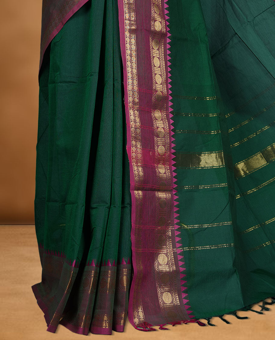Dark green colour chettinad cotton saree featuring Elegant plain body, contrast Meganta colour border with gold zari chakra and temple border, pallu and paired with matching blouse.