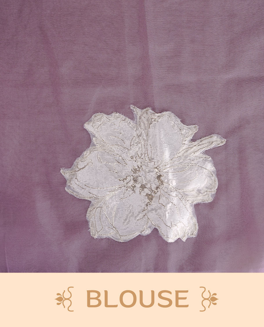 Lavender colour semi organza saree featuring white floral & gold thread pattern, highlighting scalp design border, paired with matching blouse piece.
