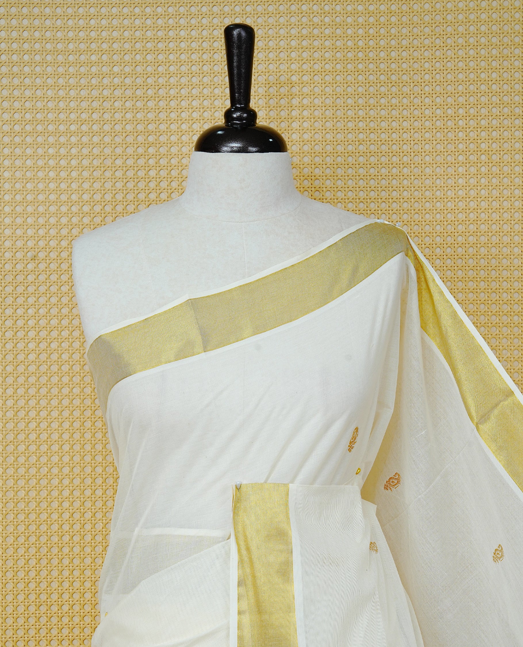 Cream Colour Cotton Kerala Saree Featuring Delicate Gold Leaf  Pattern Across The Body, Enhanced With A Traditional Gold Zari Border, A Gold Peacock Motifs &  Striped Gold Zari Pallu, Finished With A Matching Blouse Piece
