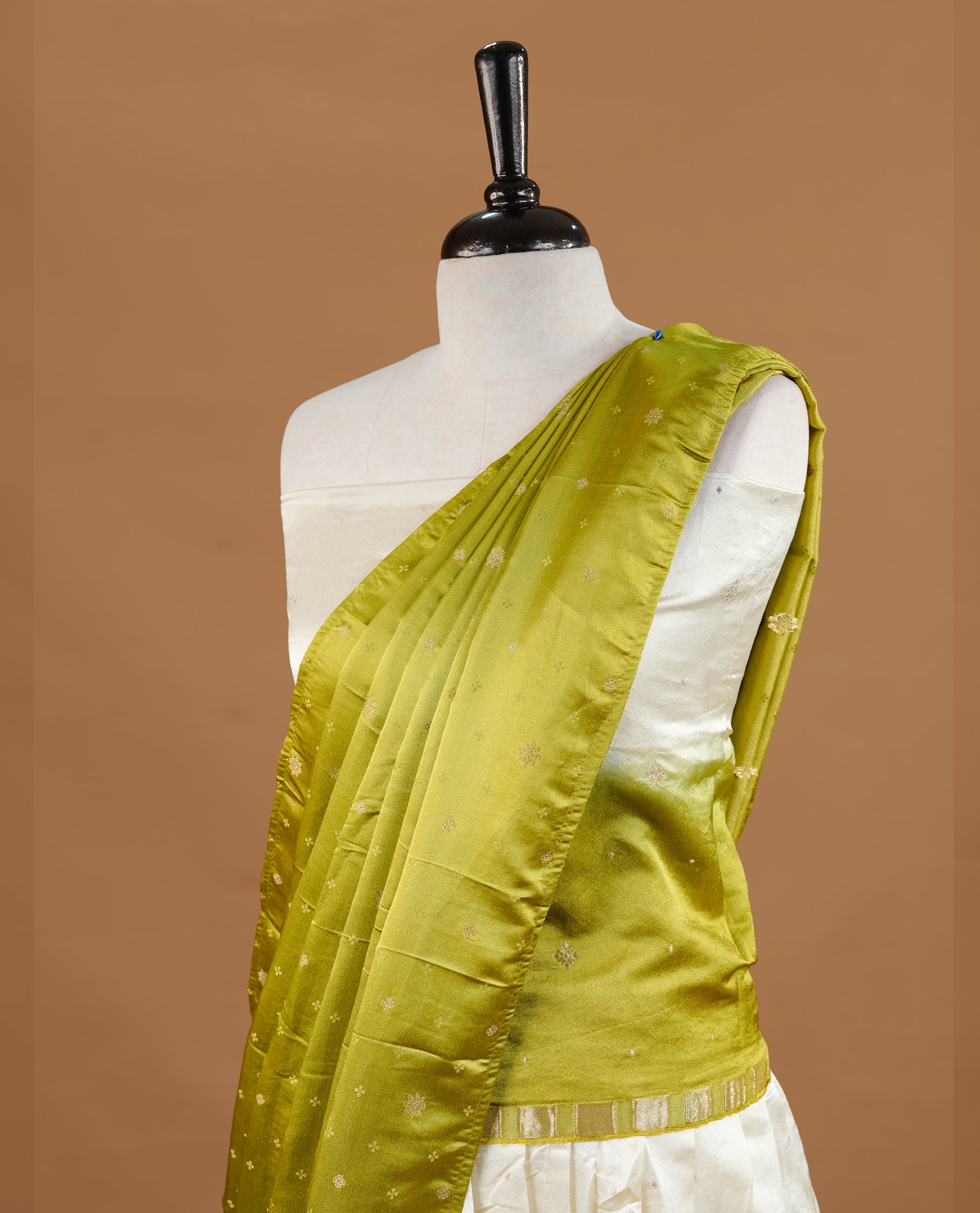 Off white colour semi stitched half saree featuring elegant zari buttas on the body, paired with a contrast pastel green border and matching striped dupatta,paired with matching blouse piece.