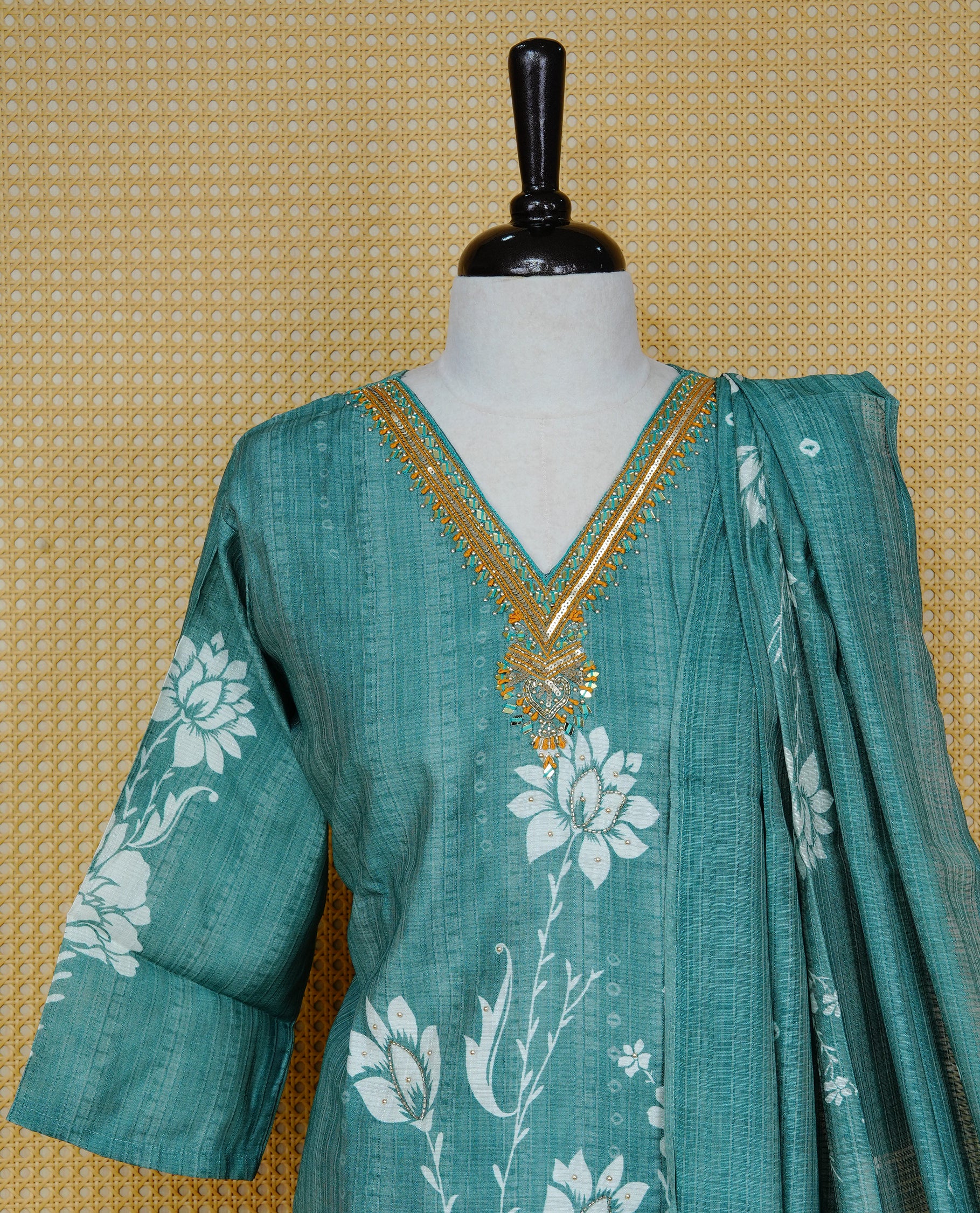 Teal green colour churidar set with floral prints and mirror embellishments on the V-neckline, paired with a matching printed dupatta and solid pants.