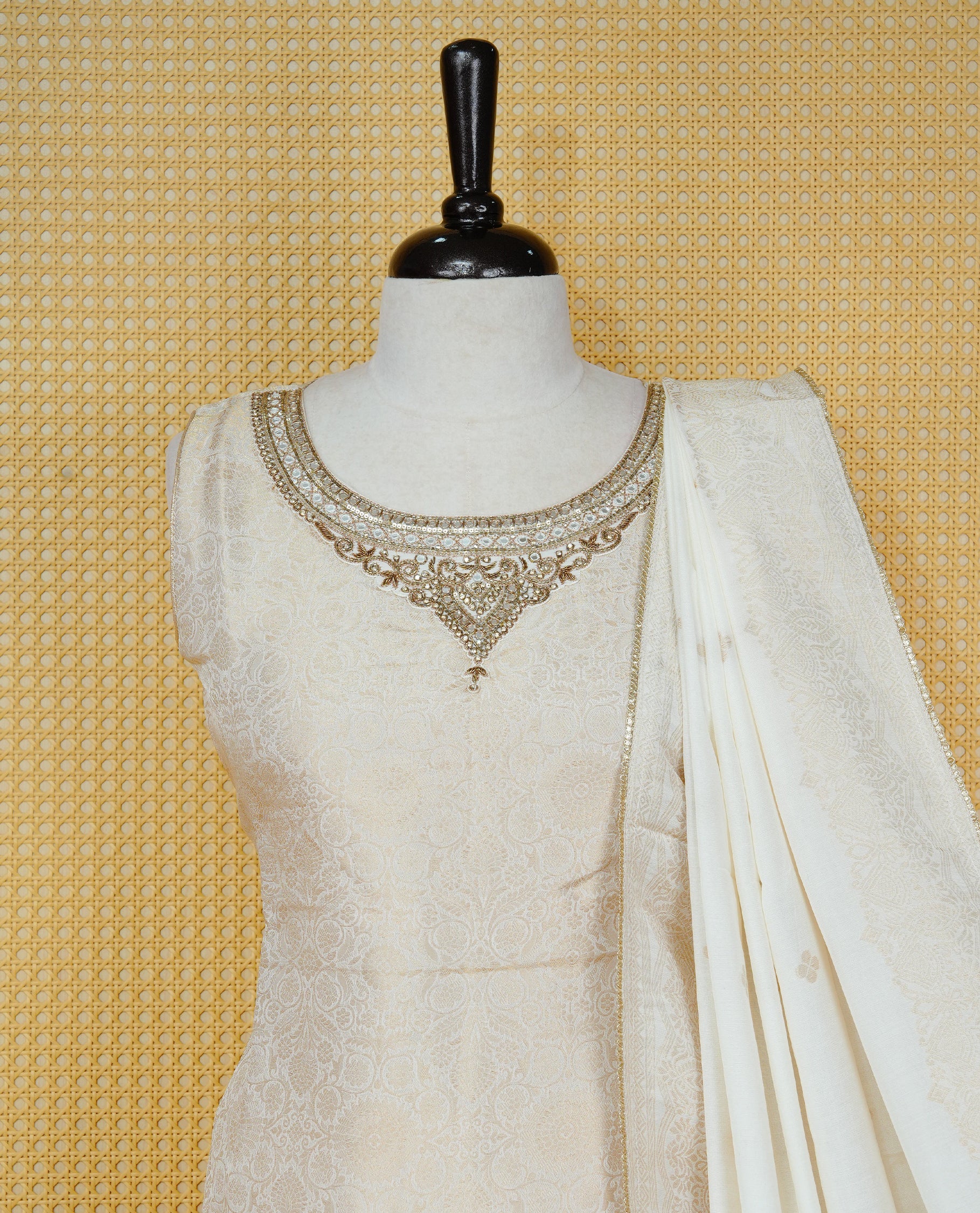 Cream colour churidar set featuring an all-over woven floral pattern and an intricately embellished neckline, paired with matching solid pants and a woven dupatta.