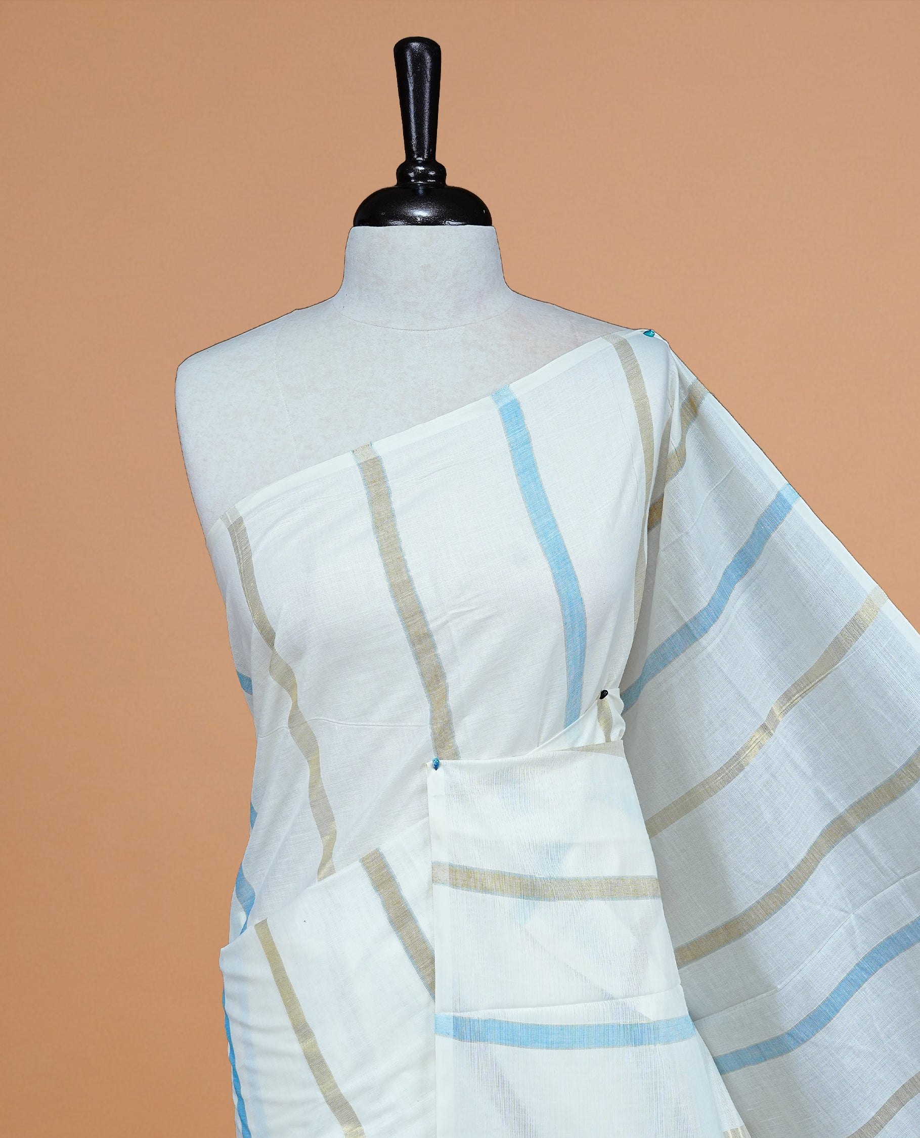 Cream Colour Cotton Kerala Saree Featuring Light Blue & Gold Zari Strips On The Body & Pallu, Paired With A Matching Blouse Piece.