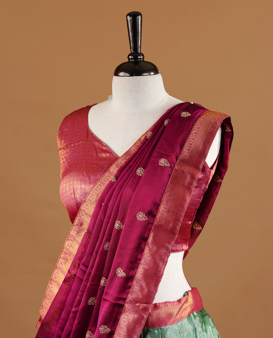 Green colour Half saree featuring green colour skirt with contrast magenta colour traditional border, paired with matching stitched blouse, matching dupatta.