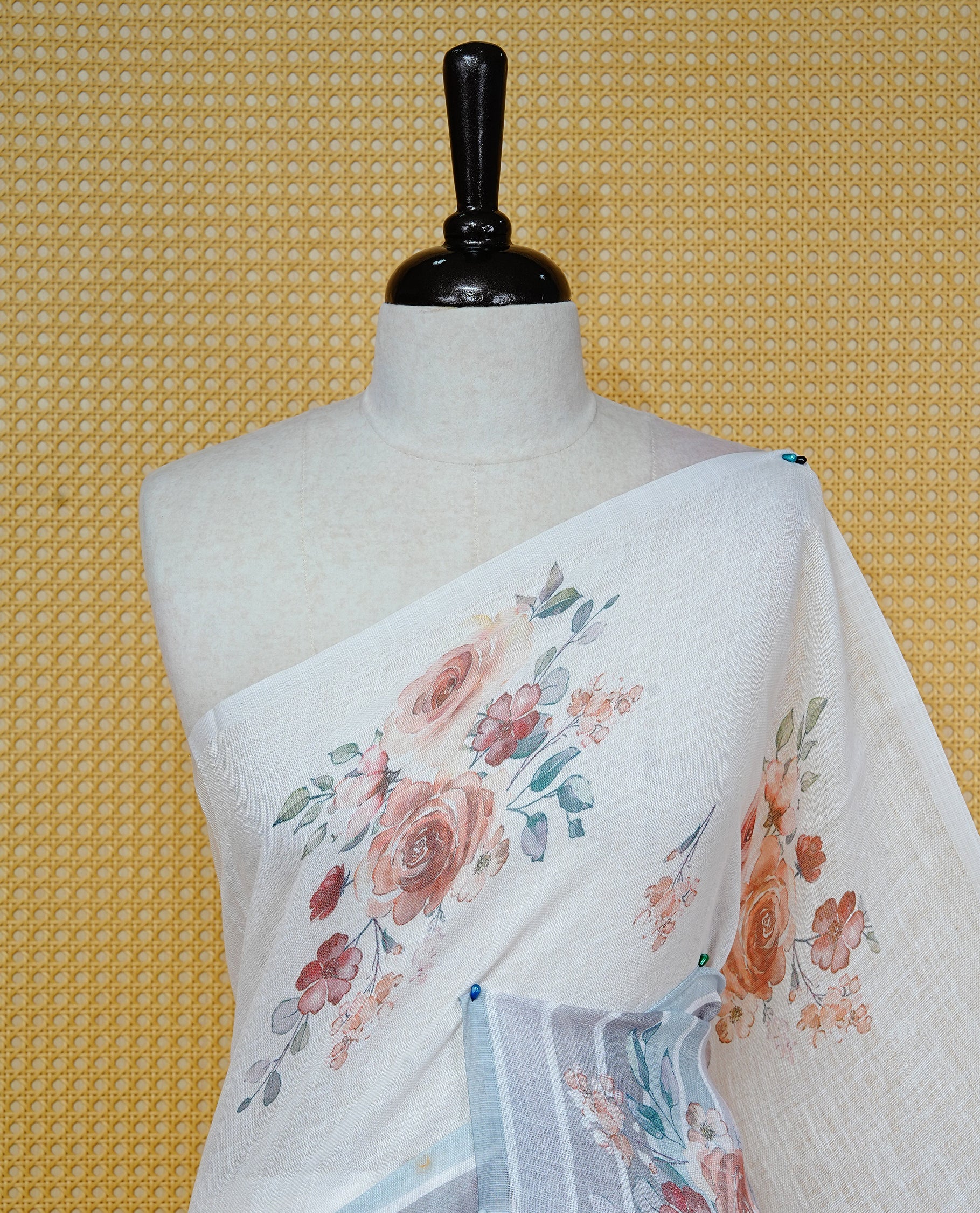 Cream colour semi linen saree featuring Floral printed buttas on body, complemented by contrast Grey colour border, comes with matching blouse piece.