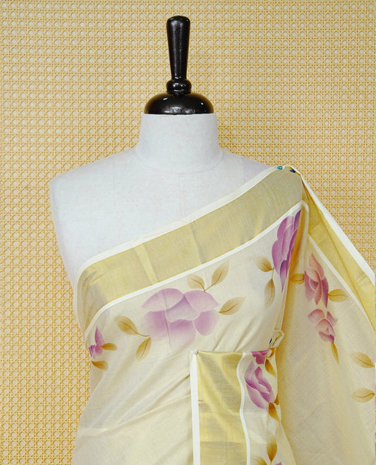 Cream Colour Tissue Kerala Saree Featuring Digital Purple Rose Prints Across The Body, Enhanced With A Gold Zari Border , Finished With Purple & Cream Tassels And A Matching Blouse Piece