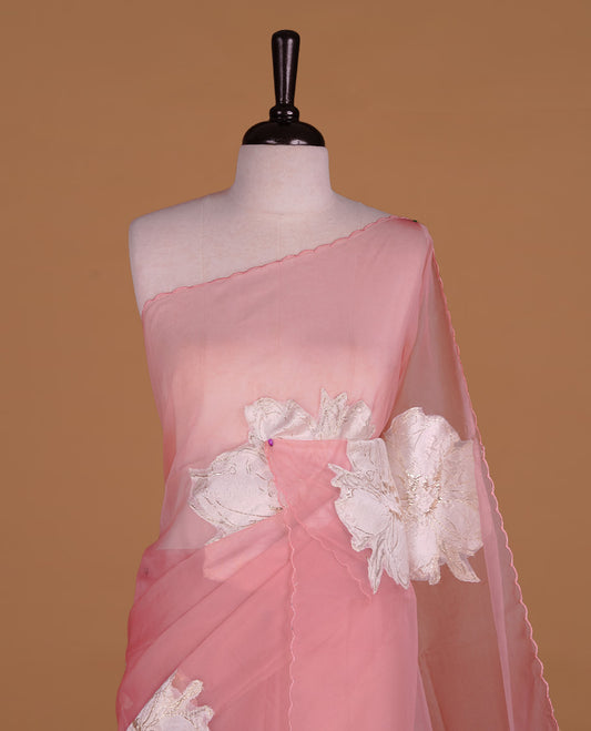 Pastel pink colour semi organza saree featuring white floral & gold thread pattern, highlighting scalp design border, paired with matching blouse piece.