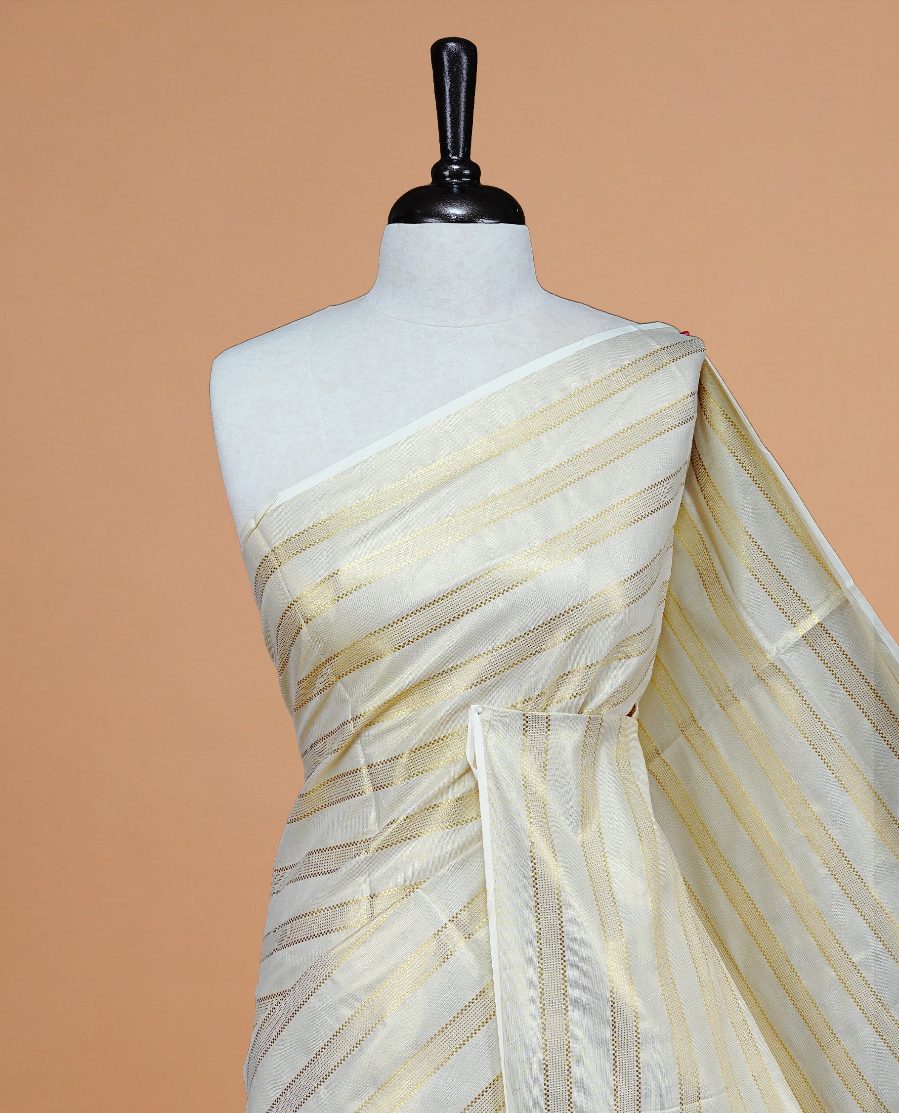 Cream Colour Tissue Kerala Saree Featuring Classy Gold zari stripes on Body, Enriched By Gold Zari Border, Paired With A Matching Blouse Piece.