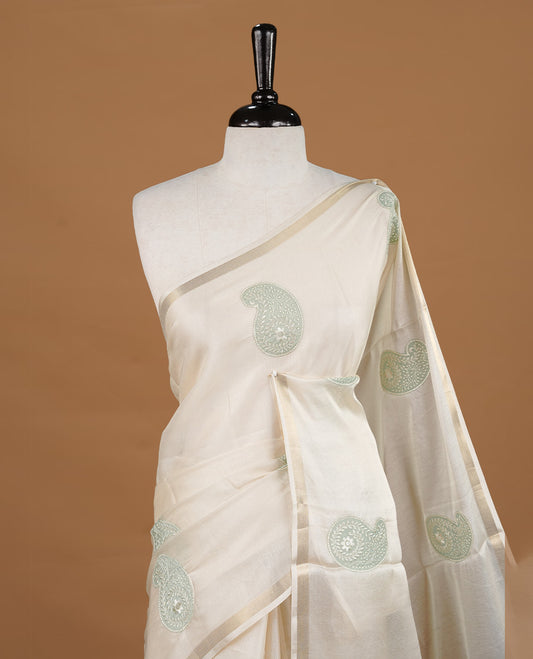 Cream colour Tussar saree featuring Light olive colour Mango pattern with chikankari embroidery work, highlighting gold zari simple border, paired with matching unstitched blouse.