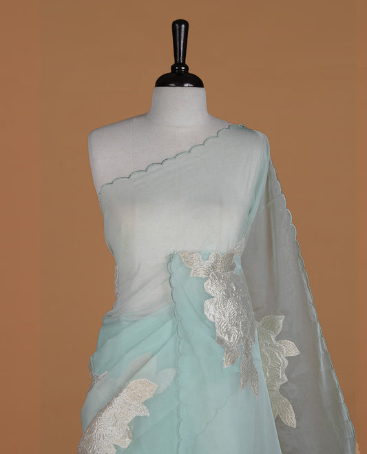 Light mint colour semi organza saree featuring white floral & gold thread pattern, highlighting scalp design border, paired with matching blouse piece.