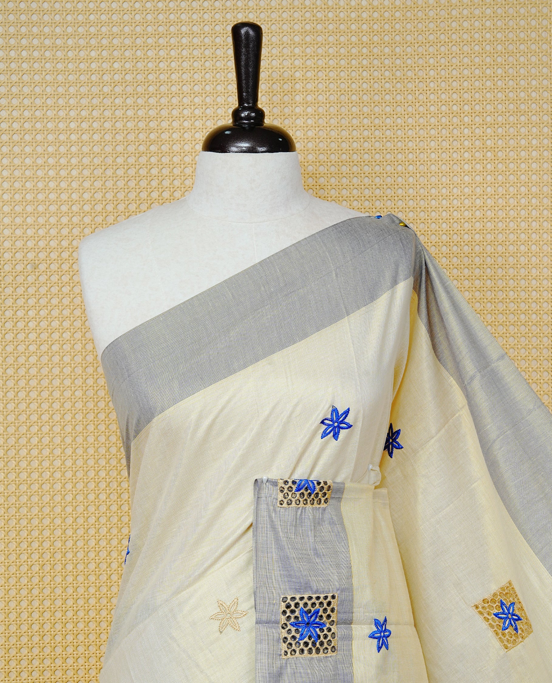 Cream Colour Tissue Kerala Saree Featuring Delicate Blue Floral Embroidery Work Across The Body, Enhanced With A Light Blue Zari Border And A Rich Blue & Gold Zari Pallu, Finished With Blue Tassels And A Matching Blouse Piece