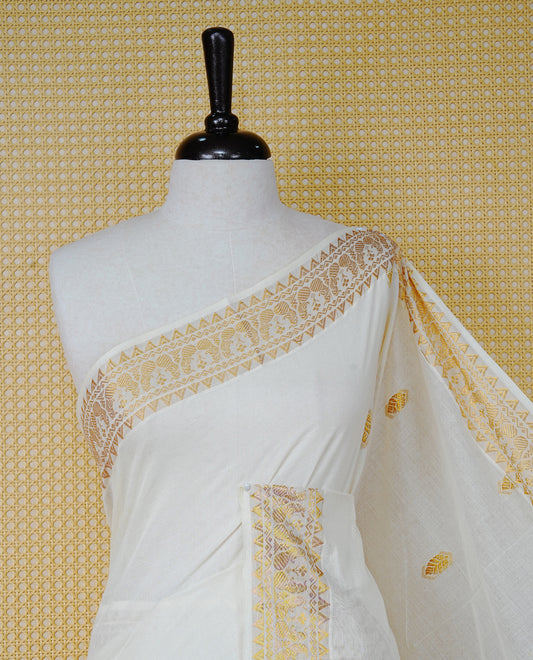 Cream Colour Cotton Kerala Saree Featuring Gold Buttas on the Body, a Classy Gold Zari Border, and a Traditional Green Colour Lord Krishna Thread work and Gold Zari Pallu, Paired with a Matching Blouse Piece.