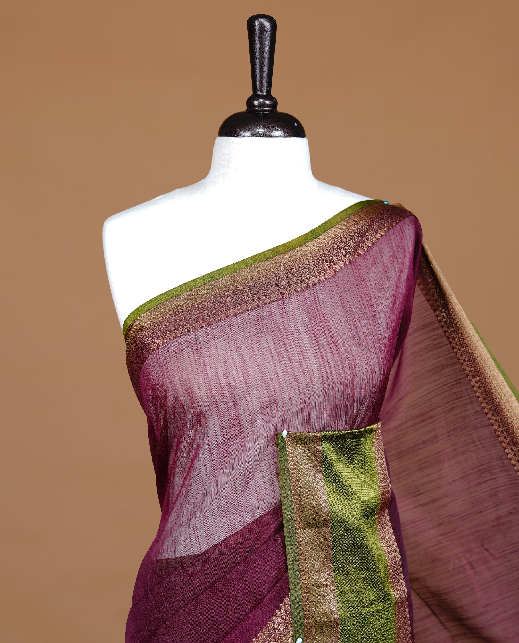 Maroon colour Semi linen saree featuring Elegant plain body, complemented by contrast Green colour With Antique zari border, paired with matching blouse piece.