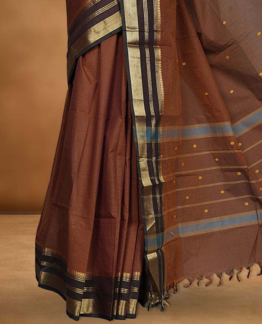 Brown colour chettinad cotton saree featuring small gold zari buttas on body highlighting contrast dark chocolate colour with gold zari traditional border, pallu and paired with matching blouse piece.