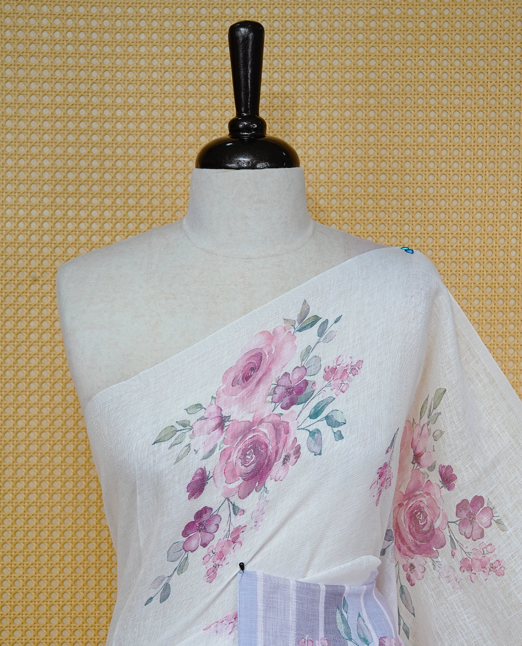 Cream colour semi linen saree featuring Pink colour floral print on body, complemented by contrast Strip pattern border, comes with matching blouse piece.