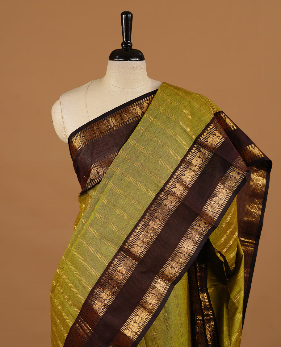 Olive colour chettinad cotton saree featuring gold zari stripes on body, complemented by dark chocolate colour with zari border, paired with matching blouse piece.