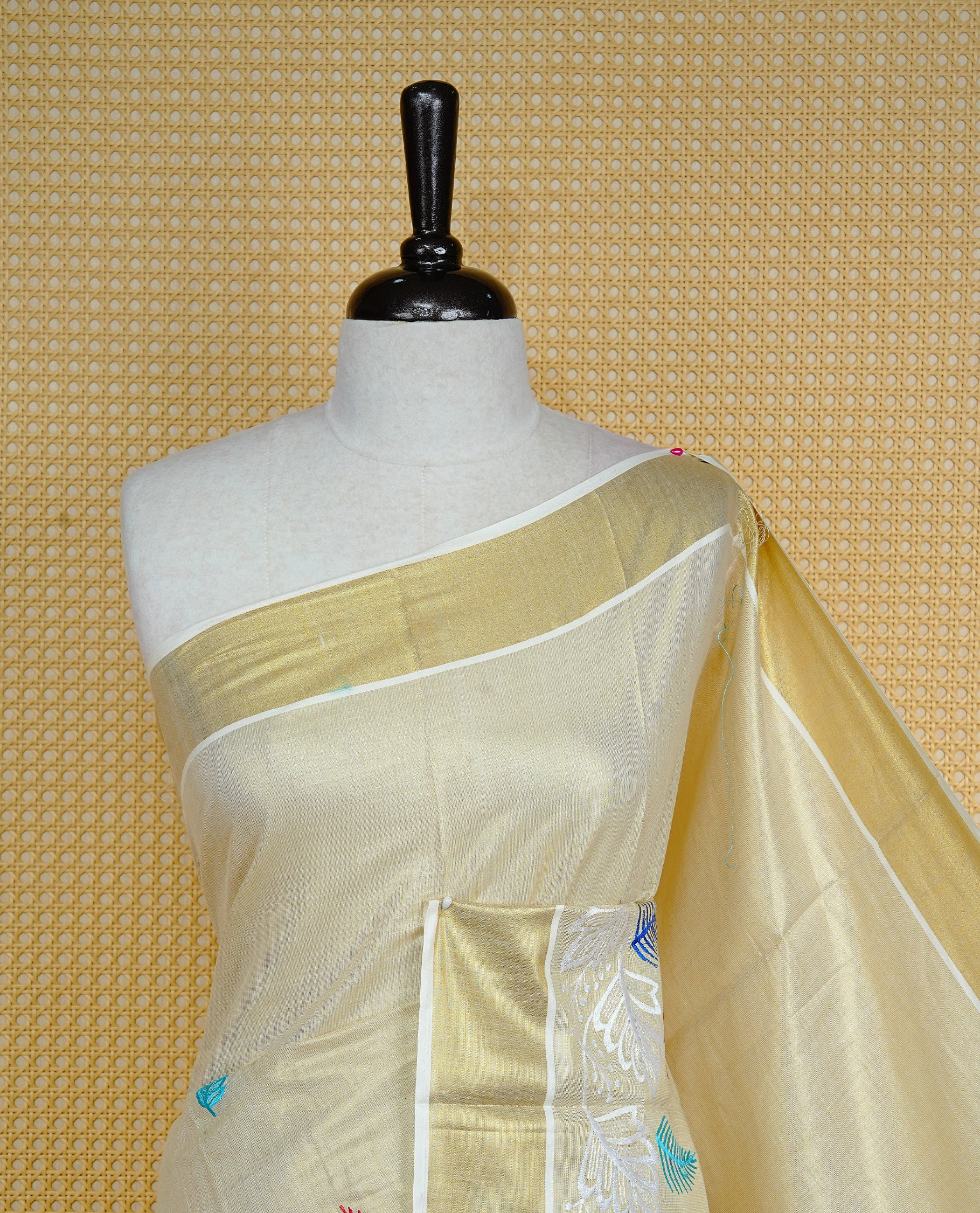 Cream colour Tissue kerala saree featuring Embroidery buttas on body, complemented by Leaf thread work & kasavu kara, comes with matching blouse piece.