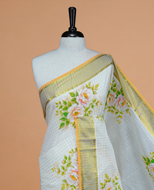 Cream Colour Kerala Saree Featuring Gold Zari Checks On The Body, Enhanced By A Gold Zari Border With Floral Prints And A Matching Pallu, Paired With A Matching Blouse Piece.