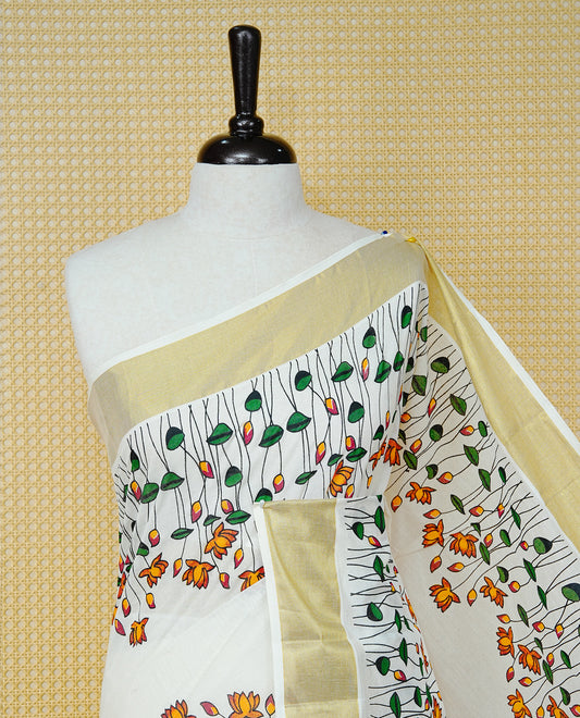 Cream Colour Cotton Kerala Saree Featuring Floral And Lotus Motifs On Body, With A Classic Gold Zari Border & A Gold Zari Pallu, Paired With A Matching Blouse Piece.