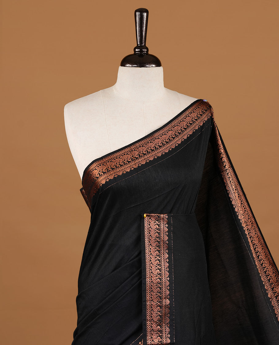 Black colour kalyani cotton saree featuring gold zari motifs on body, highlighting self colour with Antique gold zari border, paired with matching blouse piece.