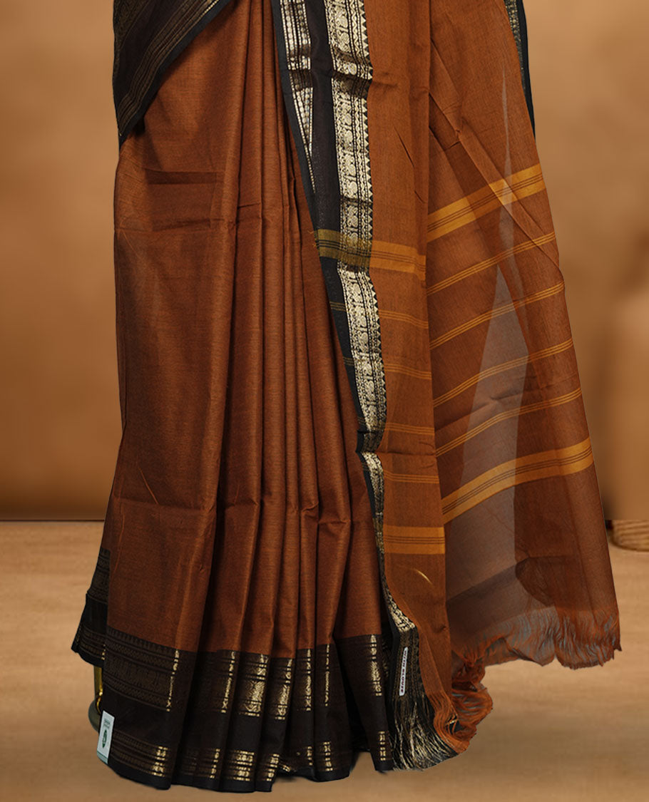 Burnt orange colour chettinad cotton saree featuring plain body, contrast Chocolate brown colour with traditional gold zari border paired with matching blouse.