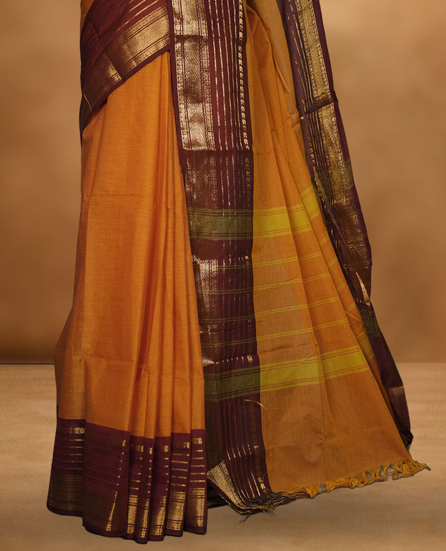 Orange colour chettinad cotton saree featuring plain body, contrast burgundy colour with traditional gold zari border paired with matching blouse.