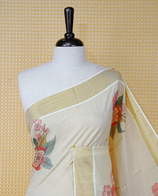 Cream Colour Tissue Kerala Saree Featuring Vibrant Digital Floral Prints Printed On Body & Pallu, Beautifully Enhanced With A Classic Gold Zari Border And Red & Blue  Tassels. Paired With A Matching Blouse Piece.