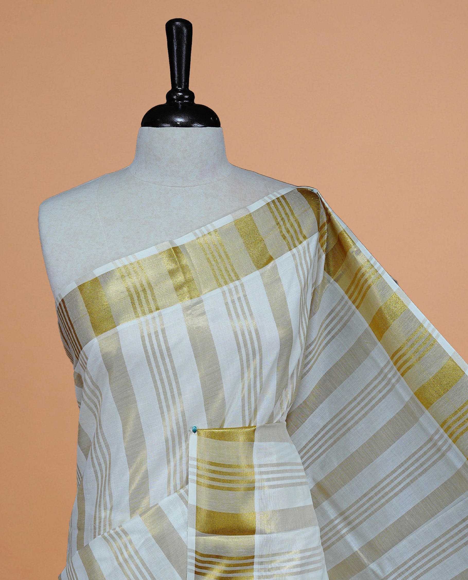 Cream Colour Cotton Kerala Saree Featuring Gold zari stripes On The Body & Classy Gold zari border, Paired With A Matching Blouse Piece.