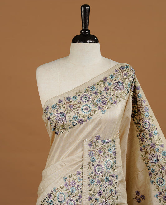 Cream grey colour Semi Tussar silk saree features an intricate, multi colored Kashmiri Kashida style floral embroidered border and scattered motifs, paired with a matching unstitched blouse piece.