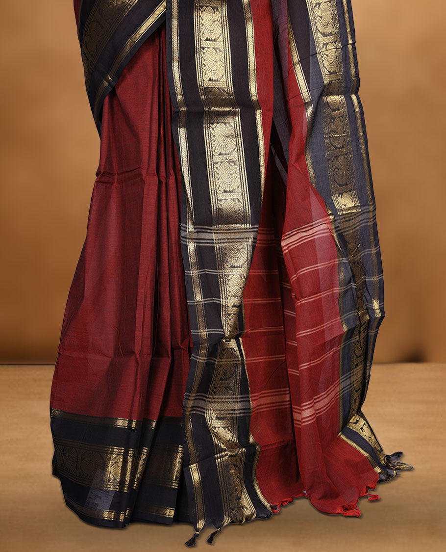 Maroon colour chettinad cotton saree featuring plain body, contrast black colour with traditional gold zari border paired with matching blouse.