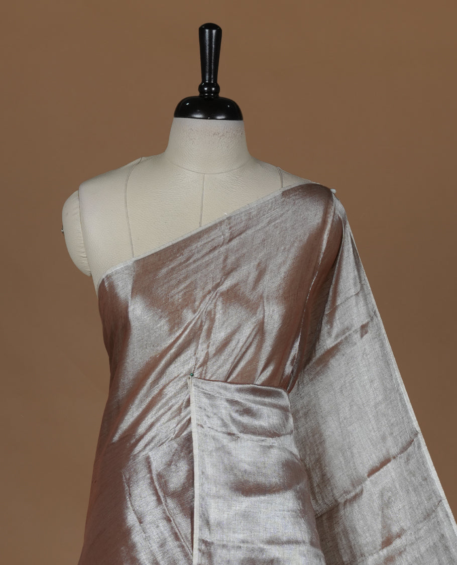 Copper colour semi tissue saree featuring an elegant plain body, designed without a border and comes without a blouse piece.