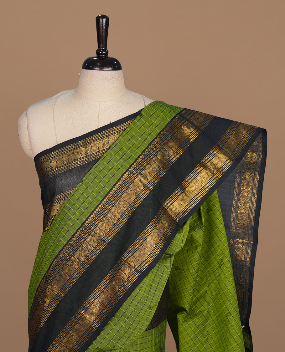 Green colour chettinad cotton saree featuring check pattern on body, complemented by contrast black with gold zari border, paired with matching blouse piece.