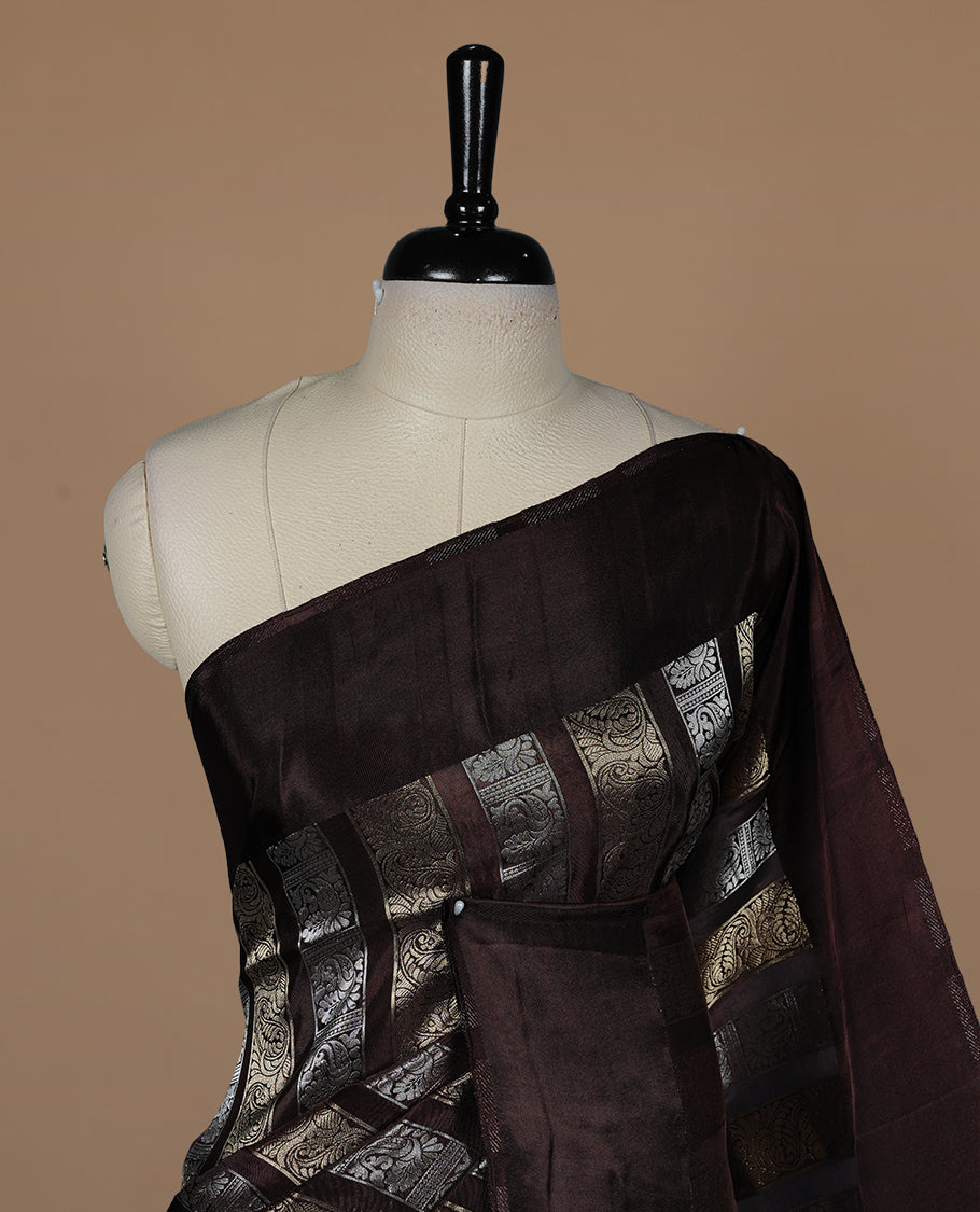 Chocolate colour banaras crepe saree featuring gold & silver zari design stripes on body, complemented by self colour border, paired with matching blouse piece.