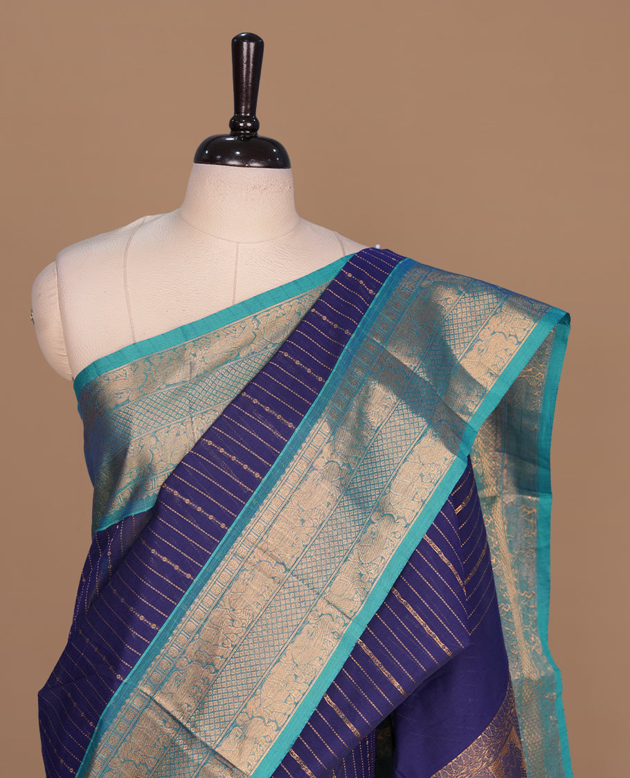 Navy blue colour chettinad saree featuring gold zari stripes on body, complemented by contrast Aqua colour with traditional border, paired with matching blouse piece.