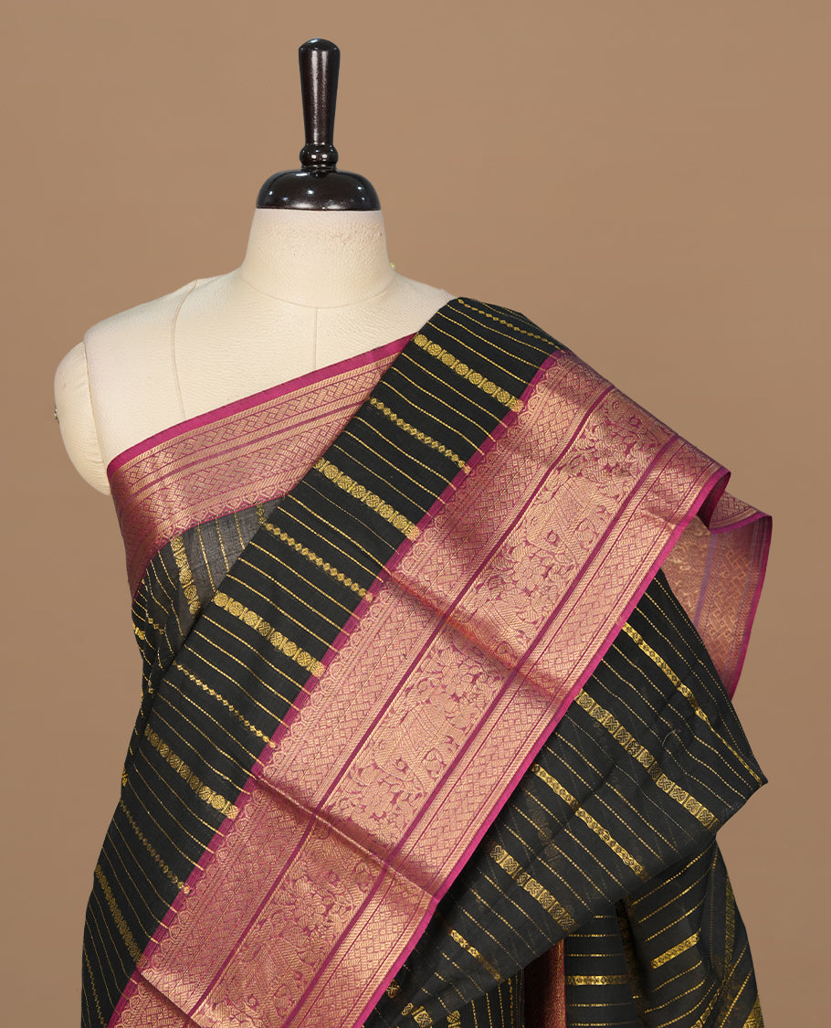 Black colour chettinad saree featuring gold zari stripes on body, complemented by contrast magenta colour with traditional border, paired with matching blouse piece.